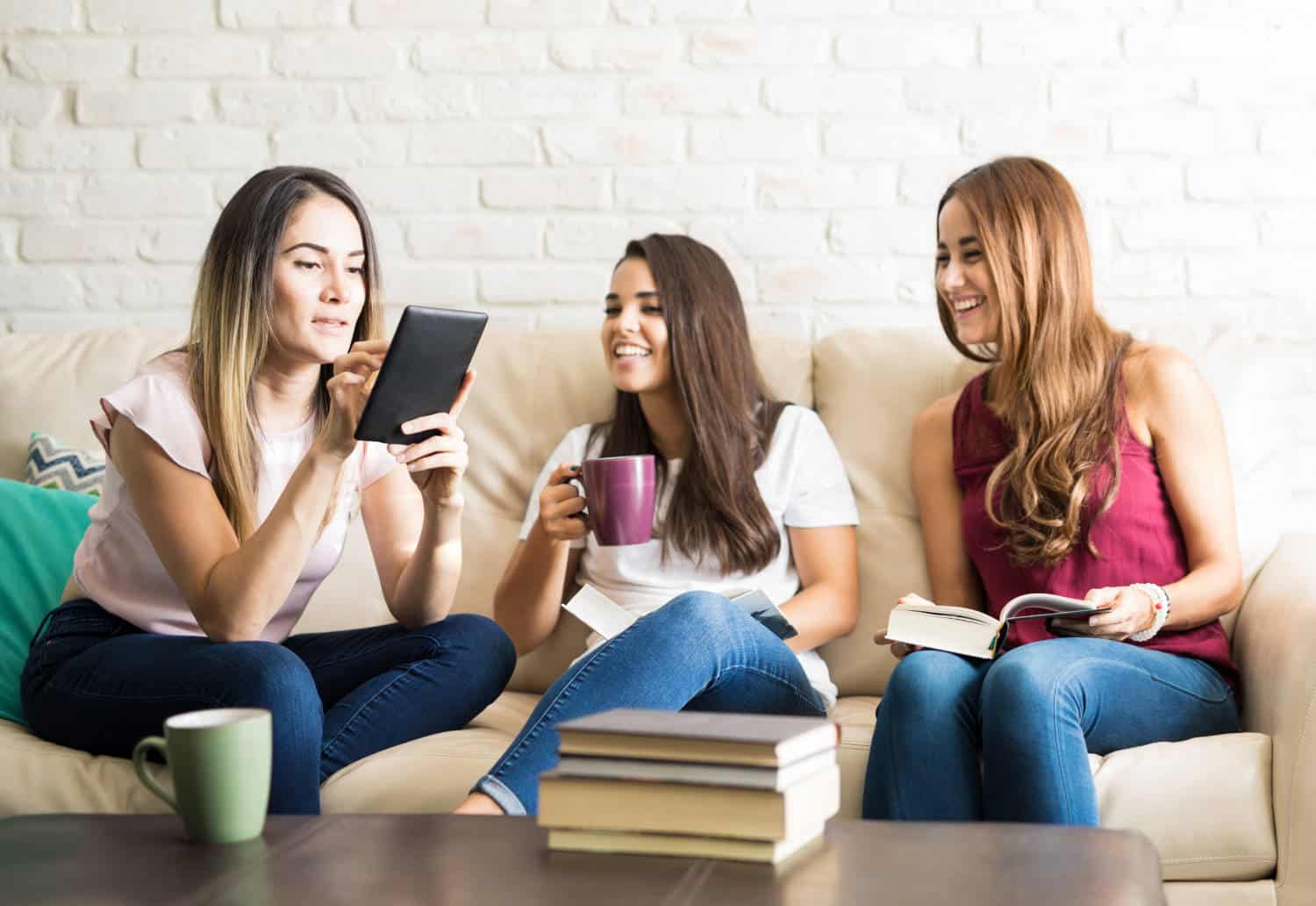 Photo of three young ladies sitting on a couch and reading books